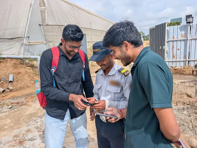 Two members of the InfraaPass team showing a security guard the app on his phone at a construction site